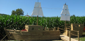 A giant wood ship with white sails sits at the entrance of a corn maze.