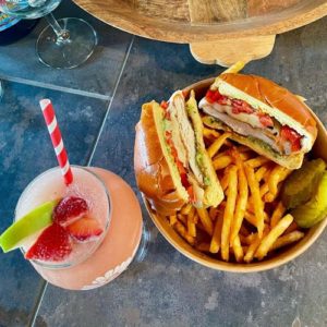 A crispy chicken sandwich with fries and a wine frose